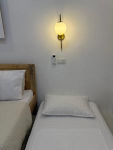 two beds in a room with a light on the wall at Ivorys Guesthouse in Panglao Island