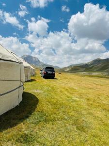 a car parked in a field next to some tents at NOMAD KEL-SUU Yurt Camp in Kol-Suu