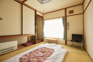 a bedroom with a large bed and a window at 旅館おぎた Ryokan Ogita - near Shiraoi Station in Shiraoi