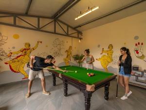 a group of people standing around a pool table at The Hosteller Kodaikanal in Kodaikānāl +12 photos