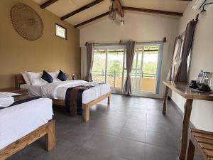 a bedroom with two beds and a large window at Bardiya Nature Lodge in Belā