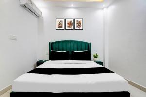a bedroom with a large bed with a green headboard at Hotel O Jaimantri Palace in Bihār Sharīf +29 photos
