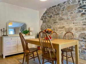 a dining room table with chairs and a stone wall at Bronafon in Rhyl