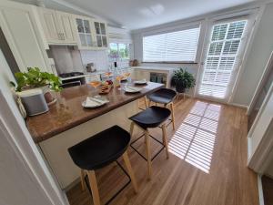 a kitchen with a island with two chairs and a counter top at Finchy Cottage in Beechworth