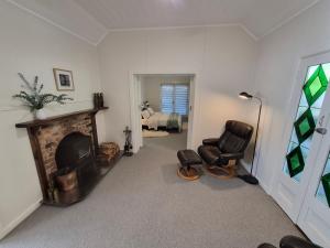 a living room with two chairs and a fireplace at Finchy Cottage in Beechworth