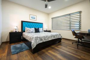 a bedroom with a bed with a blue headboard and a desk at Mar y Sol 15th Floor 3BR 2 BA Condo with pool in Rosarito