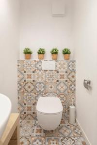 a bathroom with a toilet with potted plants on the wall at New Apartments Škofije Ankaran in Koper +25 photos
