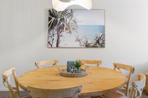 a wooden table with chairs and a picture of the beach at Seashells - 3BR Marcoola Beach Resort in Marcoola +25 photos