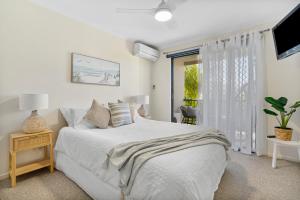 a white bedroom with a bed and a window at Seashells - 3BR Marcoola Beach Resort in Marcoola