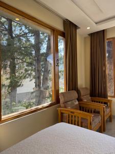 a bedroom with a bed and a chair and a window at Northlanders Guest House Skardu in Skardu