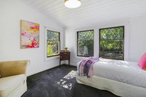 a bedroom with a bed and a chair and windows at Marianna's Lakeside Cottage in Beechworth