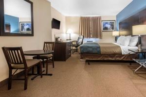 a hotel room with a bed and a table and chairs at Econo Lodge in Sudbury +20 photos