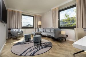 a living room with a couch and chairs and windows at DoubleTree by Hilton Berlin Ku'damm in Berlin