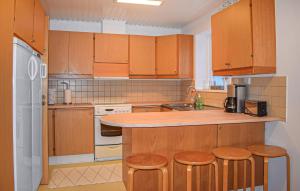 a kitchen with wooden cabinets and bar stools at 3 Bedroom Nice Home In Simrishamn in Simrishamn