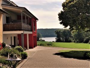 a red building with a balcony and a lake at Feriendomizil Carmen Hofmann in Absberg