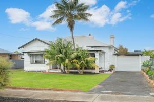 a white house with palm trees in front of it at Busselton Central Accommodation in Busselton