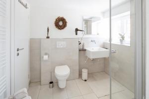 a white bathroom with a toilet and a sink at Tiny Ferienwohnung am Stadtpark in Schwäbisch Hall +5 photos