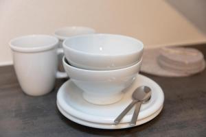 a white coffee cup and spoon on a plate at Tiny Ferienwohnung am Stadtpark in Schwäbisch Hall
