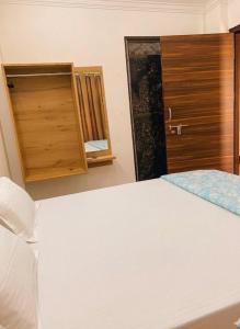 a bedroom with a white bed and a wooden door at Baloonrooms in Gorakhpur