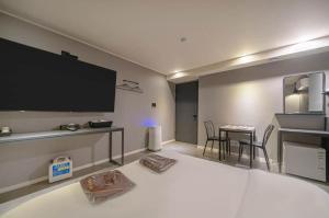 a living room with a tv and a table with chairs at Hotel HL in Seoul