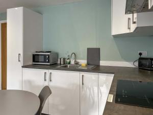 a kitchen with a sink and a microwave on a counter at Peebles Apartment in Peebles