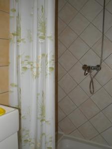 a shower with a white shower curtain with plants on it at Apartment Medulin 1 in Medulin
