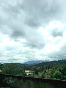 a person standing on a wall with a view of the mountains at Hillside Home in Kundasale +4 photos