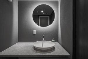 a bathroom with a sink and a round mirror at Gran Hills in Chitose