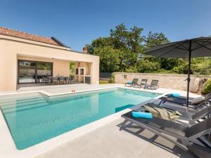 a swimming pool with two chairs and an umbrella at Villa Giulia by IstriaLux in Manjadvorci