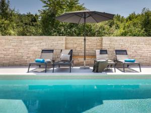 three chairs and an umbrella next to a pool at Villa Giulia by IstriaLux in Manjadvorci