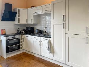 a white kitchen with white cabinets and a stove at Embleton House - Uk51597 in Berwick-Upon-Tweed