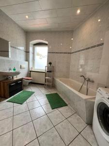 a bathroom with a tub and a sink and a washing machine at Fortuna Inn Salzmünde in Salzatal