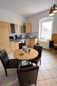 a kitchen with a wooden table and chairs and a table at Fortuna Inn Salzmünde in Salzatal