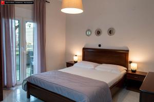 a bedroom with a bed with two lamps and a balcony at Mokos Rooms in Perdika