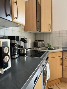 a kitchen with wooden cabinets and a black counter top at Fortuna Inn Salzmünde in Salzatal +2 photos