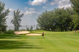 a person standing on a green golf course at Clover Greens Golf Course & Resort - Attibele, Hosur in Sarjāpur +81 photos