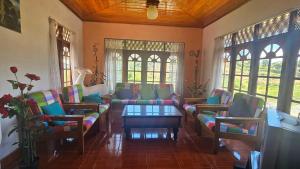 a living room with couches and a table and windows at Aurora Residence Nuwara Eliya in Nuwara Eliya
