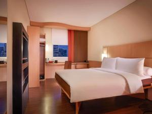 a bedroom with a large white bed and a kitchen at Ibis Surabaya City Center in Surabaya +48 photos
