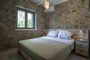 a bedroom with a bed and a stone wall at Βίλα Αοιδή in Galaxidi +49 photos