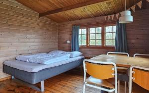 a bedroom with a bed and a table and chairs at Bygholm Camping og aktiviteter in Vesløs