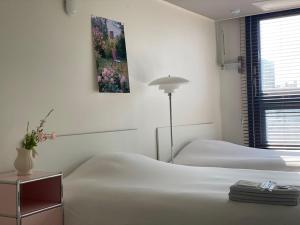a white bedroom with two beds and a lamp at Little Suite Daegu-Central Residential Hotel in Daegu