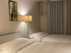 a bedroom with two white beds and a lamp at Little Suite Daegu-Central Residential Hotel in Daegu