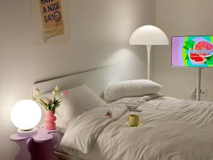 a white bed with a lamp and a cup on it at Little Suite Daegu-Central Residential Hotel in Daegu