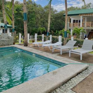 a swimming pool with chaise lounge chairs next to a house at Punta Private Beach Resort in San Teodoro
