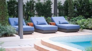 two blue lounge chairs next to a swimming pool at The Akyra Bangkok 11 in Bangkok