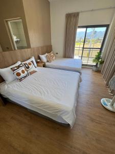 two beds in a hotel room with a large window at MM No6 Villa in Luodong