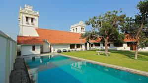 a swimming pool in front of a building with a church at Monsoon Villa in Puttalam