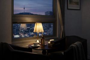a room with a table with a lamp and a window at Hotel Atrium Jongno in Seoul