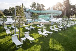 a group of white chairs and tables with a water slide at Hotel Park Punat managed by Falkensteiner in Punat