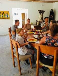 a group of people sitting at a table eating pizza at Paje lounge in Paje